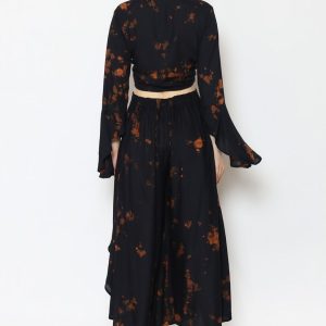A person is wearing a black two-piece outfit with an orange tie-dye pattern. The top features long sleeves and a cropped design, paired with a high-waisted, loose-fitting ruffle skirt. The view is from the back against a plain white background. A person is wearing a black two-piece outfit with an orange tie-dye pattern. The top features long sleeves and a cropped design, paired with a high-waisted, loose-fitting ruffle skirt. The view is from the back against a plain white background.