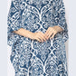 A person wearing a stylish blue and white patterned caftan with their hands gently clasped in front. The detailed design features intricate floral and geometric shapes, creating an elegant and timeless look.