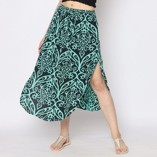 Person wearing a black and teal skirt with side slits, paired elegantly with a black top and beige sandals. The background is plain white.